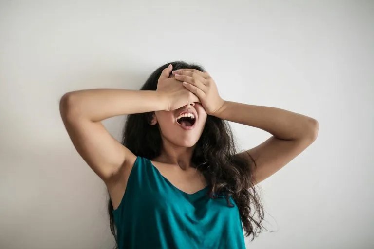 Femme exprimant une émotion avec les mains sur le visage – parler de soi en français