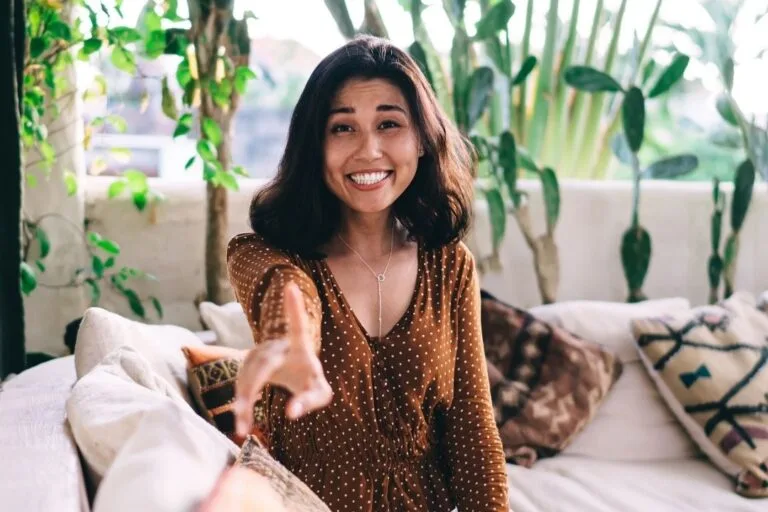 Femme d'une cinquantaine d'année souriante pointant du doigt pour expliquer comment parler de la ménopause en français.